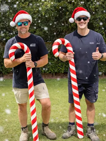 Two of the crew in Santa hats holding giant candy canes, Christmas 2025