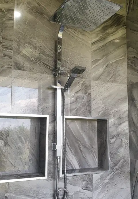 A tiled shower with a rain head and two wall niches, from the Woodward Google listing